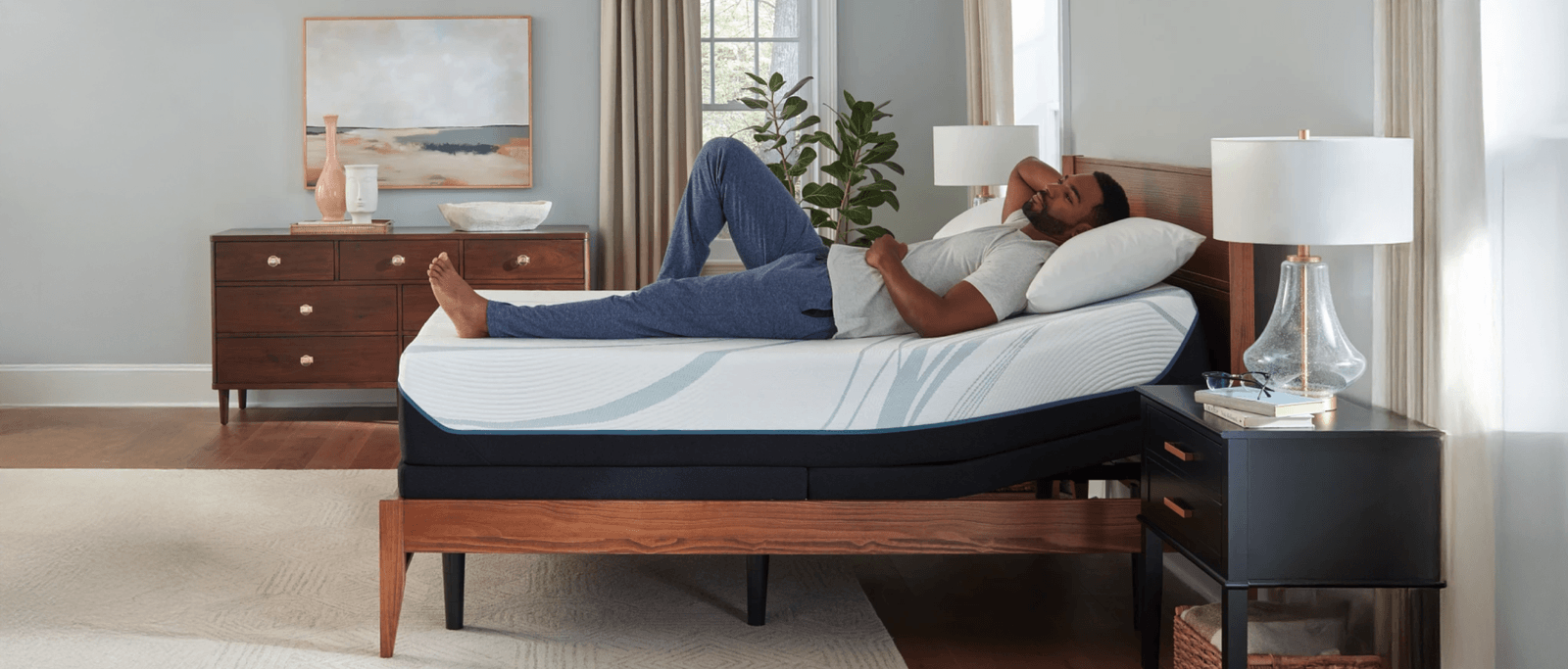 man relaxing on an Adapt mattress with the head of the bed slightly titled by the adjustable base