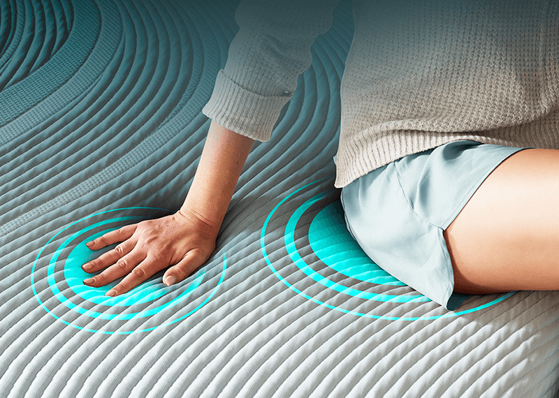 a woman sitting on a mattress showing how it gently adapts to your body