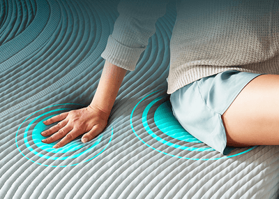 a woman sitting on a mattress showing how it gently adapts to your body