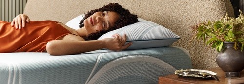 Woman laying on a TEMPUR-Adapt Mattress with a TEMPUR-Adapt Pillow