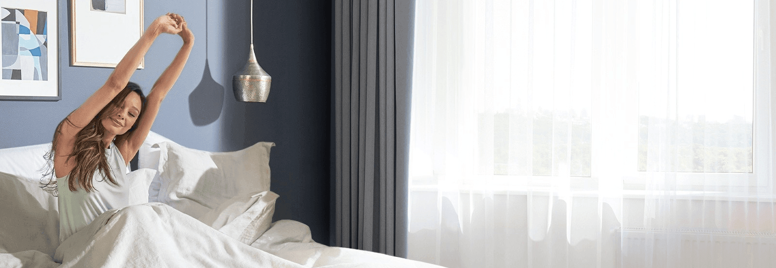 A woman in bed stretching waking up feeling refreshed after a great night sleep in a Tempur-Pedic mattress